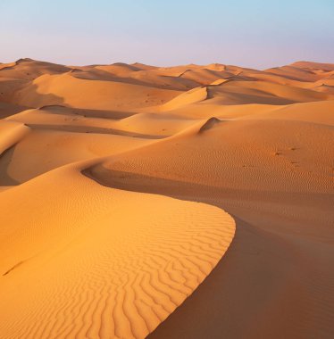 Gün batımında turuncu ve sarı kum tepeleri boş bölgede, Rub 'al Khali Çölü.