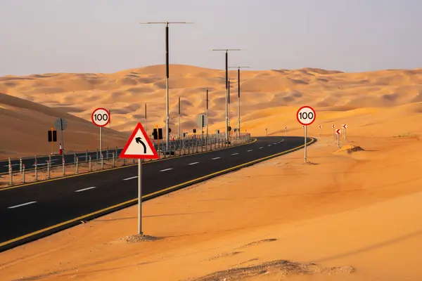 Liwa, BAE yakınlarındaki Rub Al Khali çölünde, etrafını saran yüksek kum tepeleri olan bir çöl yolu..