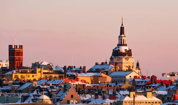 stock image Katarina Church and the roof tops of the district of Sodermalm, Stockholm, at sunset, clear sky, winter, snow. Pink orange colors.