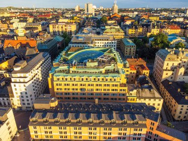 Slussen, Stockholm, İsveç, merkez köprü ve tünelin üzerindeki binaların havadan görüntüsü. İnsanların gün batımının ve manzaranın tadını çıkardığı büyük bir açık çatı barı..