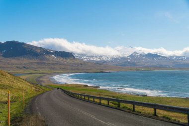 İzlanda 'nın manzaralı yolları, Snaefellsjokull stratovolcano' lu 54. yol, deniz, sahil, yeşil tarlalar ve karla kaplı dağlar. Parlak ışık, yazın başı..