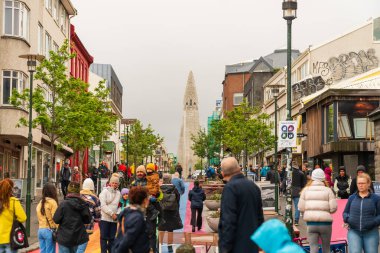 Reykjavik, İzlanda - 1 Haziran 2024: Hallgrimskirkja kilisesine giden ana cadde, fotoğraflar için poz veren turistler, yürüyen insanlar, yaz başı, gri gökyüzü.