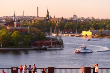 Stockholm, Sodermalm, İsveç. Fjallgatan caddesindeki turistler ve yerliler, eski kasabaya, Stockholm körfezine ve gün batımında Skeppsholmen 'in sağında olduğu Grand Hotel' e bakıyorlar.