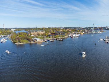 Açık bir bahar gününde İsveç 'in Stockholm kentindeki Kuzey Müzesi ve Vasa Müzesi' nin hava manzarası. Mavi gökyüzü ve yeşil ağaçlar. İnsanlar su kenarındaki parklarda dinleniyor.