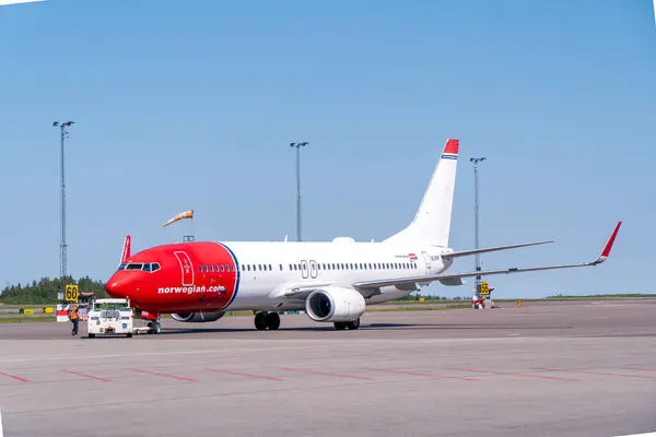 stock image Landvetter Airport, Sweden - May 21st 2024: A boeing 737-800 from Norwegian airlines, in typical red and white livery, on Gothenburg landvetter airport, with the pushback truck near by. Bright sun