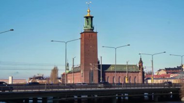 Belediye binası, Stockholm, Kungsholmen bölgesi. Ön planda şehir merkezine doğru giden merkez köprü. Arabalar geçiyor. Mavi gökyüzü, ilkbahar.