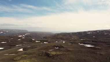 Dağ geçidi yolu Isafjordur 'a doğru, yüksek kuzey kutbu, yaz, İzlanda, yamalı kar, mavi gökyüzü, kıvrımlı yol, parlak güneş ışığı. Yolculuk, boşluk, yalnızlık. Kutup iklimi, volkanik manzaralar.