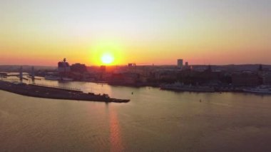 Gündoğumunda Göteborg ufuk çizgisi, hava manzarası, eski kasaba, nehir ve Hising köprüsü (Hisingbron), açık gökyüzü, turuncu ve sarı renkler.