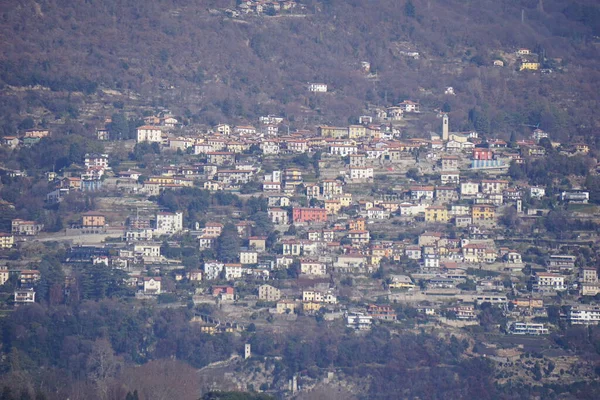 A row of houses on a hill next to a body of water