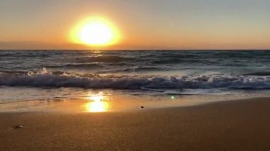 Huzurlu dalgaların üzerinde altın gün batımı