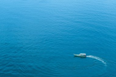 Top view, aerial view wooden fishing boat on the beach from a drone. Royalty high quality stock photo image of the wooden fishing boat on the beach. Fishing boat is mooring on clear blue beach alone