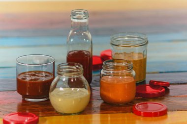 Renkli ahşap bir tabanda el yapımı baharatlı soslar - Salsas picantes he has artesanalmente en frascos de vidrio sober fondo de madera de colores