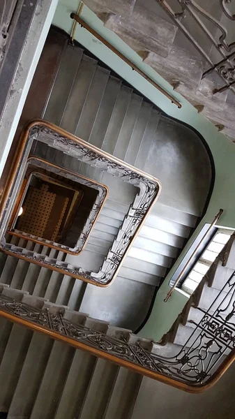A spiral staircase with metal railings in a building,A winding beauty, elegant and grand.With each step, the view changes,A new perspective, a new range.