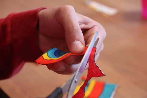 A person carefully uses scissors to cut a piece of paper, making precise and deliberate movements.