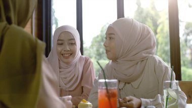 Bir grup başarılı ve hareketli Asyalı Müslüman arkadaş güneşli ve aydınlık bir günde sakin bir kahve dükkanının keyfini çıkarıyorlar.