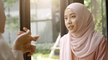 Bir grup başarılı ve hareketli Asyalı Müslüman arkadaş güneşli ve aydınlık bir günde sakin bir kahve dükkanının keyfini çıkarıyorlar.