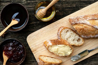 Yeni pişirilmiş geleneksel İtalyan Ciabatta ekmeklerinin ahşap bir masada servis edilmek üzere dilimlenip dilimlendiği yakın plan bir üst görüntüsü.