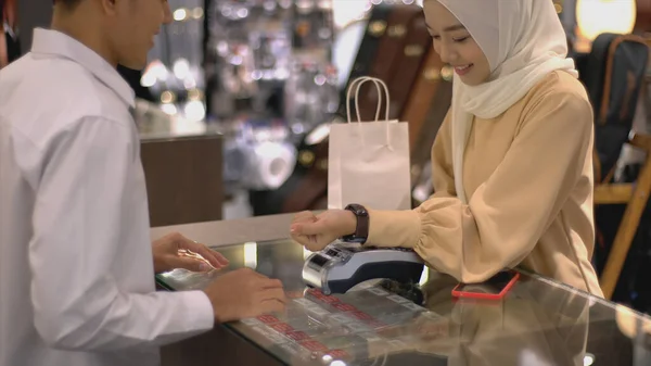 携帯電話を使用して上向きにモバイルアジアのムスリム女性 スマートウォッチは 検証と認証のためのNfc識別支払いで販売端末で製品の支払いをする — ストック写真