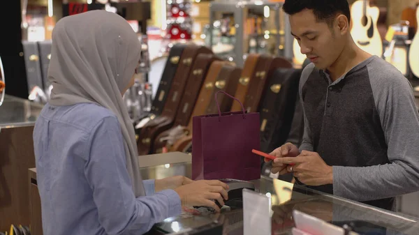 携帯電話を使用して上向きにモバイルアジアのムスリム男性 スマートウォッチは 検証と認証のためのNfc識別支払いで販売端末で製品の支払い — ストック写真