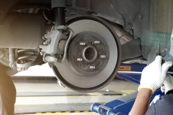 A mechanic repairing, grinding the brake disc and replacing brake pads at an auto repair shop service station - vehicle safety concept