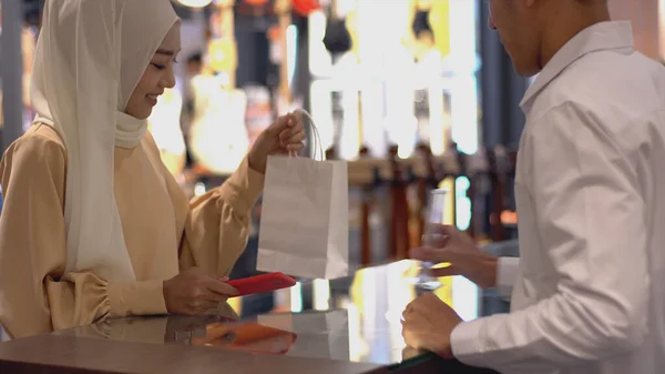 携帯電話を使用して上向きにモバイルアジアのムスリム女性 スマートウォッチは 検証と認証のためのNfc識別支払いで販売端末で製品の支払いをする — ストック写真