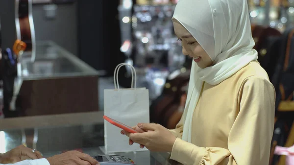一名乐观的亚洲穆斯林妇女用手机在销售终端支付产品的费用 用Nfc识别码支付验证和认证费用 — 图库照片
