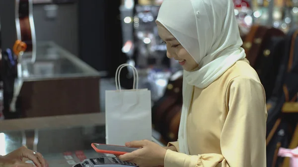 Ylöspäin Liikkuva Aasialainen Musliminainen Joka Käyttää Matkapuhelinta Älykello Maksaa Tuotteesta — kuvapankkivalokuva
