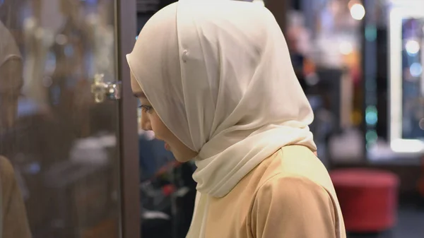 特写一位身穿传统吉吉布服饰的年轻的亚洲穆斯林妇女正在商店橱窗里搜寻商品 — 图库照片