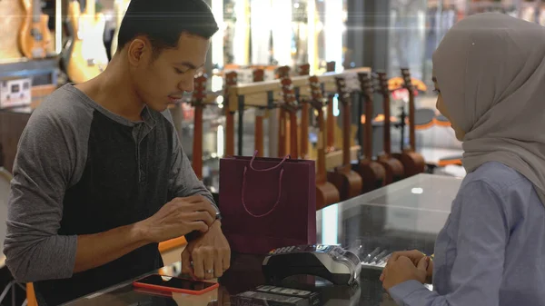 Upwardly Mobile Asian Muslim Man Using Mobile Phone Smartwatch Pay — Stock Photo, Image