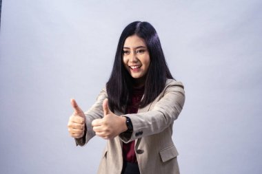 Asyalı genç bir iş kadınının portresi. Başparmak gösterisi, stüdyo çekimi, iş konsepti, izole edilmiş arka plan.
