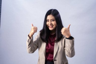 Asyalı genç bir iş kadınının portresi. Başparmak gösterme, stüdyo çekimi, iş konsepti, izole bir geçmiş.