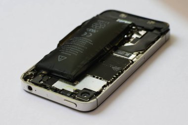 Bir cep telefonunun içinde izole edilmiş beyaz arka planda şişmiş lityum iyon polimer bataryası.