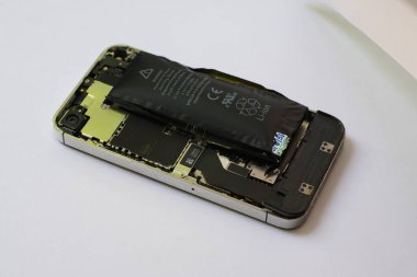 Bir cep telefonunun içinde izole edilmiş beyaz arka planda şişmiş lityum iyon polimer bataryası.