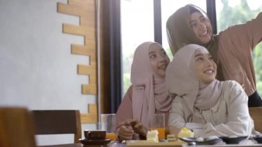 Bir grup başarılı ve hareketli Asyalı Müslüman arkadaş güneşli ve aydınlık bir günde sakin bir kahve dükkanının keyfini çıkarıyorlar.