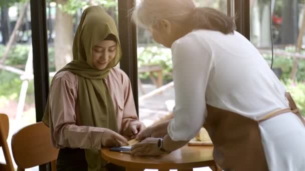 在一个阳光灿烂的日子里 一位乐观向上的亚洲穆斯林妇女在咖啡店里享受着放松的时光 — 图库视频影像