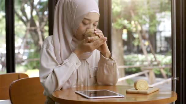 在一个阳光灿烂的日子里 一位乐观向上的亚洲穆斯林妇女在咖啡店里享受着放松的时光 — 图库视频影像