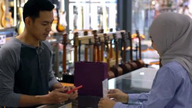 Cep telefonu kullanan üst düzey bir Asyalı Müslüman adam. NFC kimlik doğrulama ve kimlik doğrulama ödemesi ile birlikte bir satış terminalinde ürün almak için çok akıllıca bir hareket.