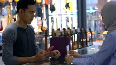 Cep telefonu kullanan üst düzey bir Asyalı Müslüman adam. NFC kimlik doğrulama ve kimlik doğrulama ödemesi ile birlikte bir satış terminalinde ürün almak için çok akıllıca bir hareket.  