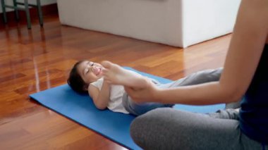 Asyalı bir anne, kızıyla yoga egzersizleri öğretir ve pratik yapar. Yoga minderleri üzerinde. Parlak, güneşli sabah oturma odalarında. 