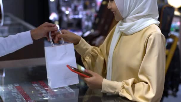 一名上流社会的亚洲穆斯林妇女使用手机 聪明的人在销售终端支付产品的费用 用Nfc识别码支付验证和认证费用 — 图库视频影像