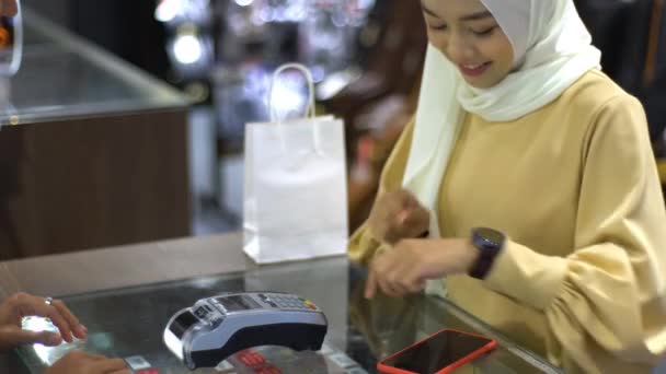 Upwardly Mobile Asian Muslim Woman Using Mobile Phone Smartwatch Pay — Stock Video