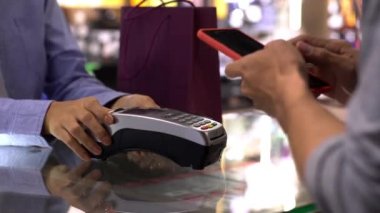 Cep telefonu kullanan üst düzey bir Asyalı Müslüman adam. NFC kimlik doğrulama ve kimlik doğrulama ödemesi ile birlikte bir satış terminalinde ürün almak için çok akıllıca bir hareket.  