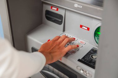 ATM 'de kadının eli kişisel şifreyi yazıyor.