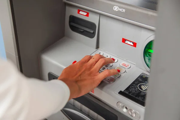 ATM 'de kadının eli kişisel şifreyi yazıyor.