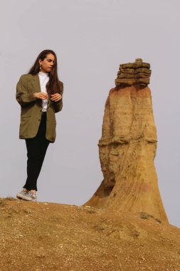 Bardenas Reales 'in kurak manzarasında dinlenen genç bir kadın, dikey fotoğraf.