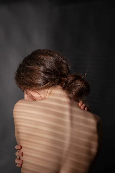 Portrait of nude female back with hair up, vertical photo.
