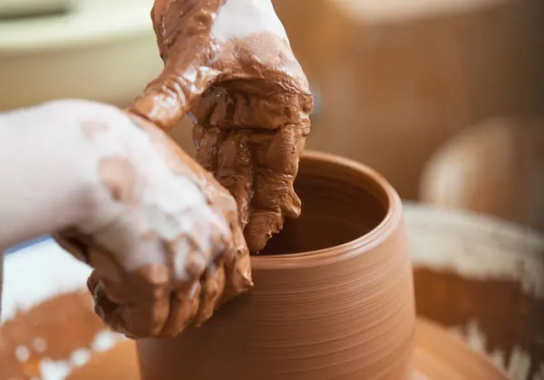 Ceramist hand making a vase with clay on the potter\'s wheel