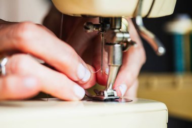 Dikiş makinesinin iğnesini batıran bir kadının ellerinin tahrip edilmesi.