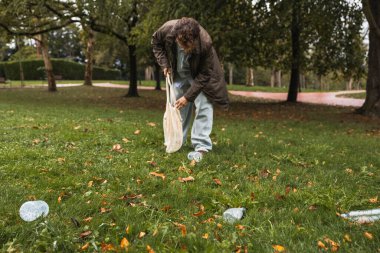 Parkta plastik torbayla plastik toplayan sıradan bir çocuk.