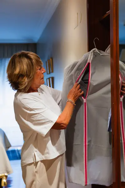 Mature woman in the dressing room sorting out the clothes